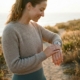Person checking their smartwatch during an outdoor walk in natural coastal setting, illustrating health and activity tracking in a wellness context